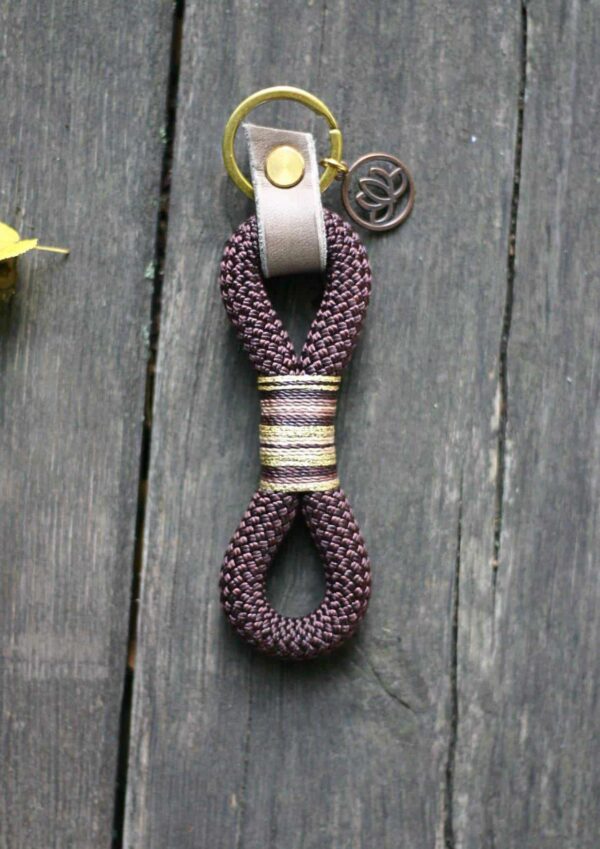 Klíčenka Venchim Klíčenka Lotosový květ. Vyrobená z lana v hnědé barvě, ozdobená světle hnědou kůží a přívěskem lotosového květu.