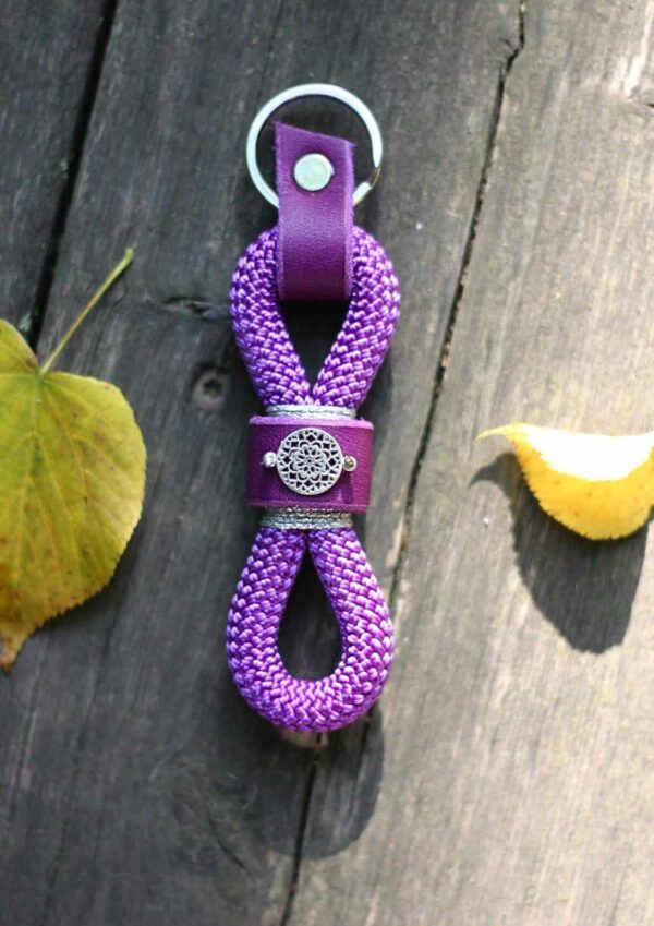 Klíčenka Venchim Klíčenka z lana ve fialové barvě, ozdobená fialovou kůží se stříbrnou mandalkou.